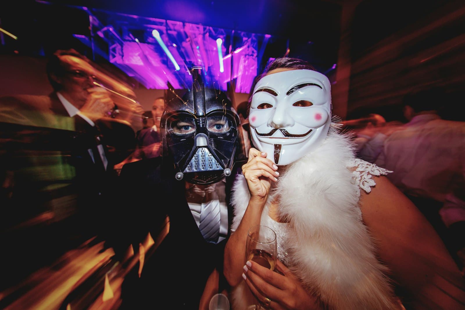 Pessoas mascaradas na pista sob luzes roxas de palco